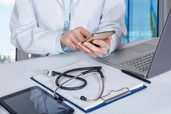 A doctor using a phone and laptop